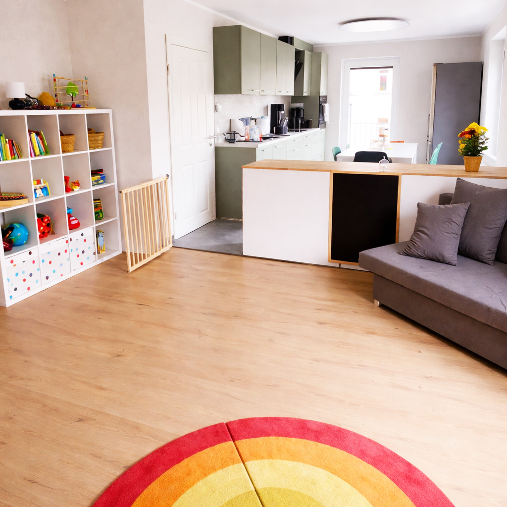 Heller Wohnraum mit offener Küche, Sofa und Spielecke für Kinder